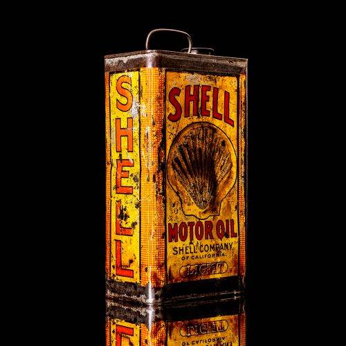 Vintage Shell oil cans with red and yellow branding from the 1900-1920 old logo Vintage Shell oil cans from 1900-1920, featuring the old logo. The photo showcases an antique tin red with yellow accents, displaying the historic Shell emblem. Shot in a studio against a solid black background