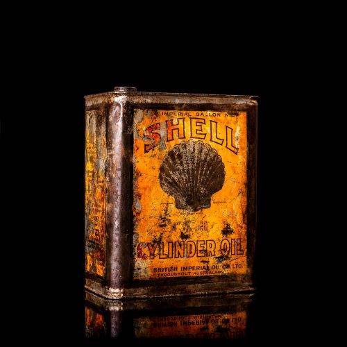 Vintage Shell oil cans with red and yellow branding from the 1900-1920 old logo Vintage Shell oil cans from 1900-1920, featuring the old logo. The photo showcases an antique tin red with yellow accents, displaying the historic Shell emblem. Shot in a studio against a solid black background