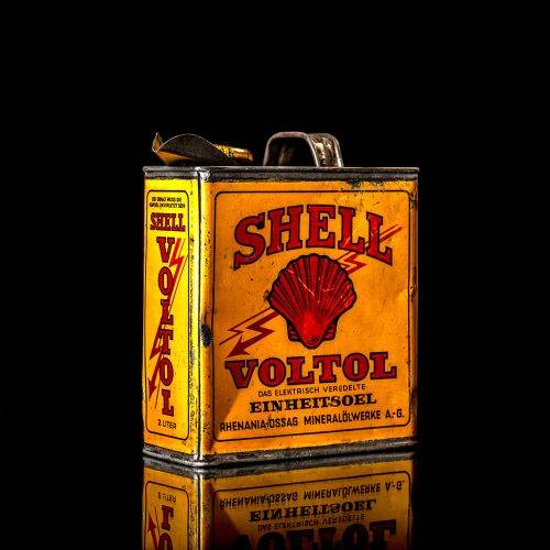 Vintage Shell oil cans with red and yellow branding from the 1920-1940 old logo Vintage Shell oil cans from 1900-1920, featuring the old logo. The photo showcases an antique tin yellow with red accenaccents, displaying the historic Shell emblem. Shot in a studio against a solid black background
