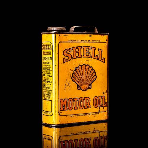 Vintage Shell oil cans with red and yellow branding from the 1920-1940 old logo Vintage Shell oil cans from 1900-1920, featuring the old logo. The photo showcases an antique tin yellow with red accenaccents, displaying the historic Shell emblem. Shot in a studio against a solid black background