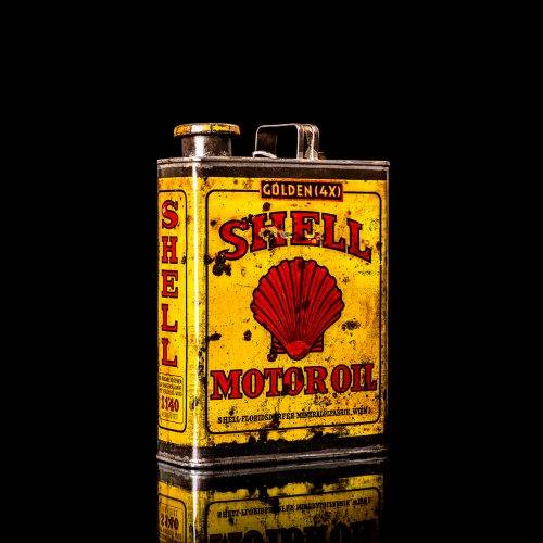 Vintage Shell oil cans with red and yellow branding from the 1920-1940 old logo Vintage Shell oil cans from 1900-1920, featuring the old logo. The photo showcases an antique tin yellow with red accenaccents, displaying the historic Shell emblem. Shot in a studio against a solid black background