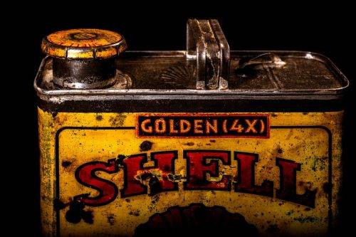 Vintage Shell oil cans with red and yellow branding from the 1920-1940 old logo Vintage Shell oil cans from 1900-1920, featuring the old logo. The photo showcases an antique tin yellow with red accenaccents, displaying the historic Shell emblem. Shot in a studio against a solid black background