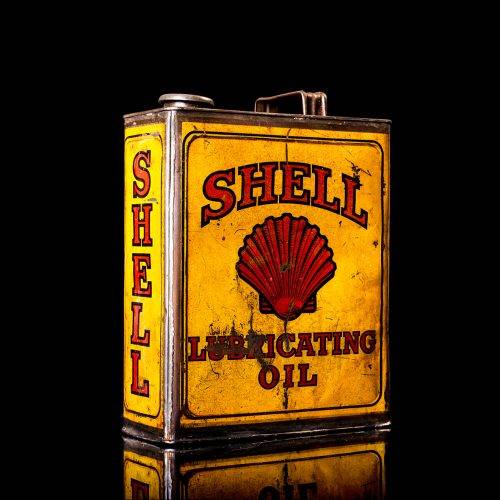 Vintage Shell oil cans with red and yellow branding from the 1920-1940 old logo Vintage Shell oil cans from 1900-1920, featuring the old logo. The photo showcases an antique tin yellow with red accenaccents, displaying the historic Shell emblem. Shot in a studio against a solid black background