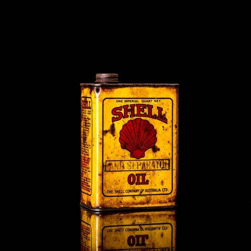 Vintage Shell oil cans with red and yellow branding from the 1920-1940 old logo Vintage Shell oil cans from 1900-1920, featuring the old logo. The photo showcases an antique tin yellow with red accenaccents, displaying the historic Shell emblem. Shot in a studio against a solid black background