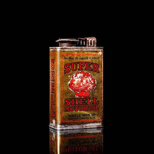 Vintage Shell oil cans with red and yellow branding from the 1920-1940 old logo Vintage Shell oil cans from 1900-1920, featuring the old logo. The photo showcases an antique tin yellow with red accenaccents, displaying the historic Shell emblem. Shot in a studio against a solid black background