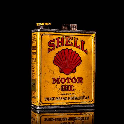 Vintage Shell oil cans with red and yellow branding from the 1920-1940 old logo Vintage Shell oil cans from 1900-1920, featuring the old logo. The photo showcases an antique tin yellow with red accenaccents, displaying the historic Shell emblem. Shot in a studio against a solid black background
