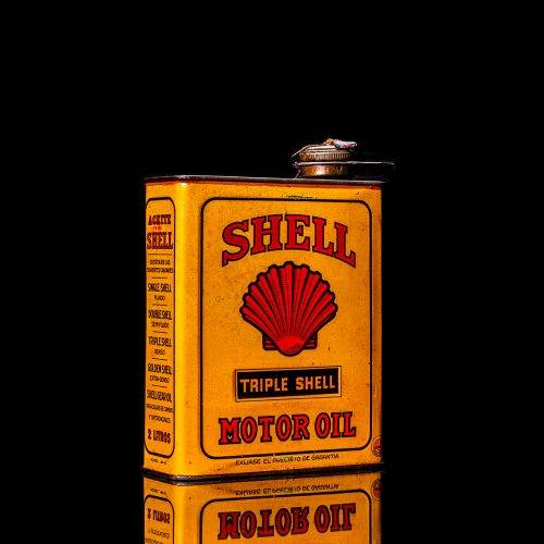 Vintage Shell oil cans with red and yellow branding from the 1920-1940 old logo Vintage Shell oil cans from 1900-1920, featuring the old logo. The photo showcases an antique tin yellow with red accenaccents, displaying the historic Shell emblem. Shot in a studio against a solid black background