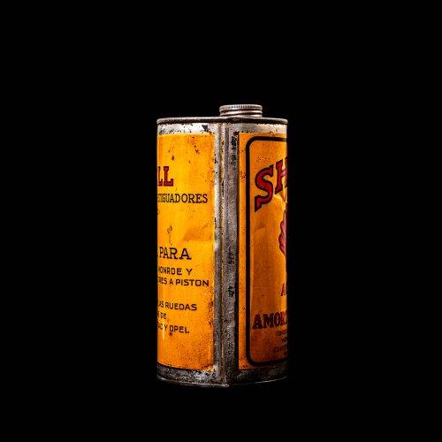 Vintage Shell oil cans with red and yellow branding from the 1920-1940 old logo Vintage Shell oil cans from 1900-1920, featuring the old logo. The photo showcases an antique tin yellow with red accenaccents, displaying the historic Shell emblem. Shot in a studio against a solid black background