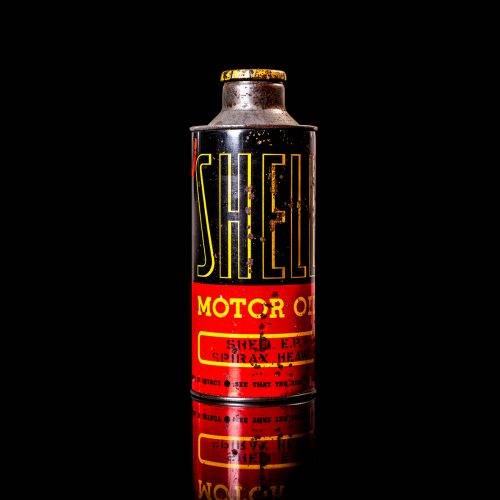 Vintage Shell oil cans with red and yellow branding from the 1920-1940 old logo Vintage Shell oil cans from 1900-1920, featuring the old logo. The photo showcases an antique tin yellow with red accenaccents, displaying the historic Shell emblem. Shot in a studio against a solid black background