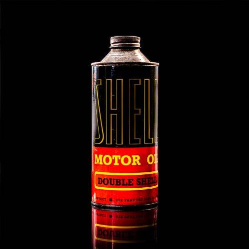 Vintage Shell oil cans with red and yellow branding from the 1920-1940 old logo Vintage Shell oil cans from 1900-1920, featuring the old logo. The photo showcases an antique tin yellow with red accenaccents, displaying the historic Shell emblem. Shot in a studio against a solid black background