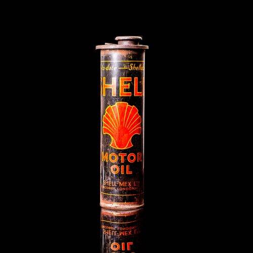 Vintage Shell oil cans with red and yellow branding from the 1920-1940 old logo Vintage Shell oil cans from 1900-1920, featuring the old logo. The photo showcases an antique tin yellow with red accenaccents, displaying the historic Shell emblem. Shot in a studio against a solid black background
