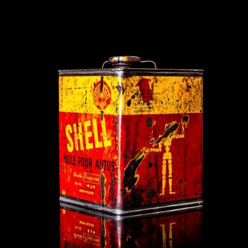 Vintage Shell oil cans with red and yellow branding from the 1920-1940 old logo Vintage Shell oil cans from 1900-1920, featuring the old logo. The photo showcases an antique tin yellow with red accenaccents, displaying the historic Shell emblem. Shot in a studio against a solid black background