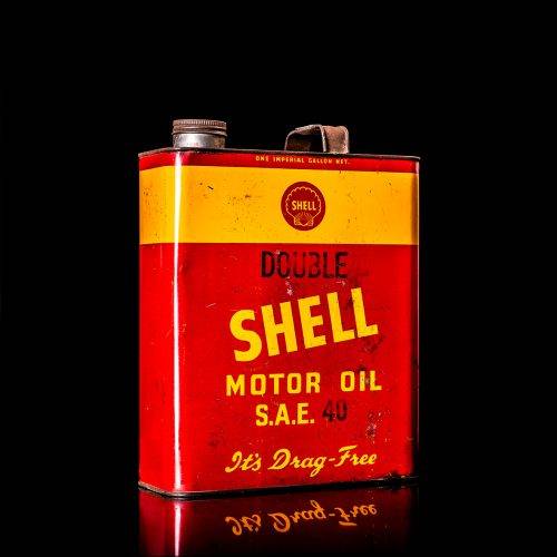 Vintage Shell oil cans with red and yellow branding from the 1920-1940 old logo Vintage Shell oil cans from 1900-1920, featuring the old logo. The photo showcases an antique tin yellow with red accenaccents, displaying the historic Shell emblem. Shot in a studio against a solid black background