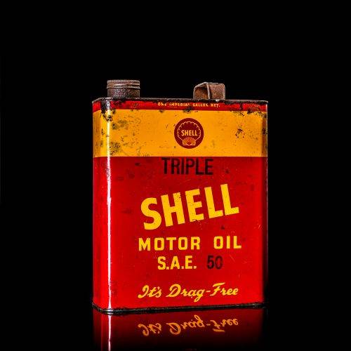 Vintage Shell oil cans with red and yellow branding from the 1920-1940 old logo Vintage Shell oil cans from 1900-1920, featuring the old logo. The photo showcases an antique tin yellow with red accenaccents, displaying the historic Shell emblem. Shot in a studio against a solid black background