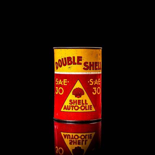 Vintage Shell oil cans with red and yellow branding from the 1920-1940 old logo Vintage Shell oil cans from 1900-1920, featuring the old logo. The photo showcases an antique tin yellow with red accenaccents, displaying the historic Shell emblem. Shot in a studio against a solid black background