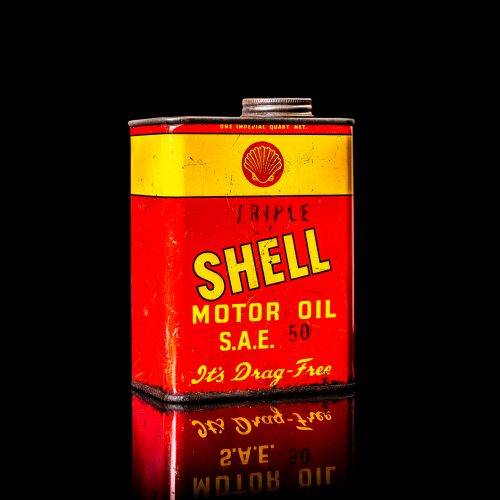 Vintage Shell oil cans with red and yellow branding from the 1920-1940 old logo Vintage Shell oil cans from 1900-1920, featuring the old logo. The photo showcases an antique tin yellow with red accenaccents, displaying the historic Shell emblem. Shot in a studio against a solid black background