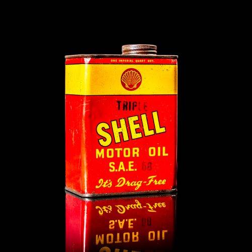 Vintage Shell oil cans with red and yellow branding from the 1920-1940 old logo Vintage Shell oil cans from 1900-1920, featuring the old logo. The photo showcases an antique tin yellow with red accenaccents, displaying the historic Shell emblem. Shot in a studio against a solid black background