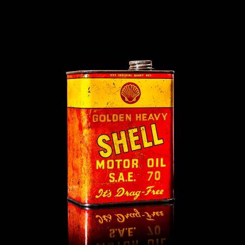 Vintage Shell oil cans with red and yellow branding from the 1920-1940 old logo Vintage Shell oil cans from 1900-1920, featuring the old logo. The photo showcases an antique tin yellow with red accenaccents, displaying the historic Shell emblem. Shot in a studio against a solid black background